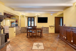A spacious kitchen with a dining area, stone walls, and a tiled floor.