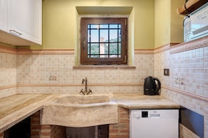 A kitchen with a built-in dishwasher, a window with a view, and a tiled backsplash.