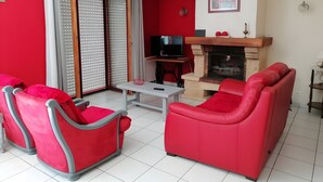 A living room with red furniture, a television, a fireplace, and a sliding glass door.