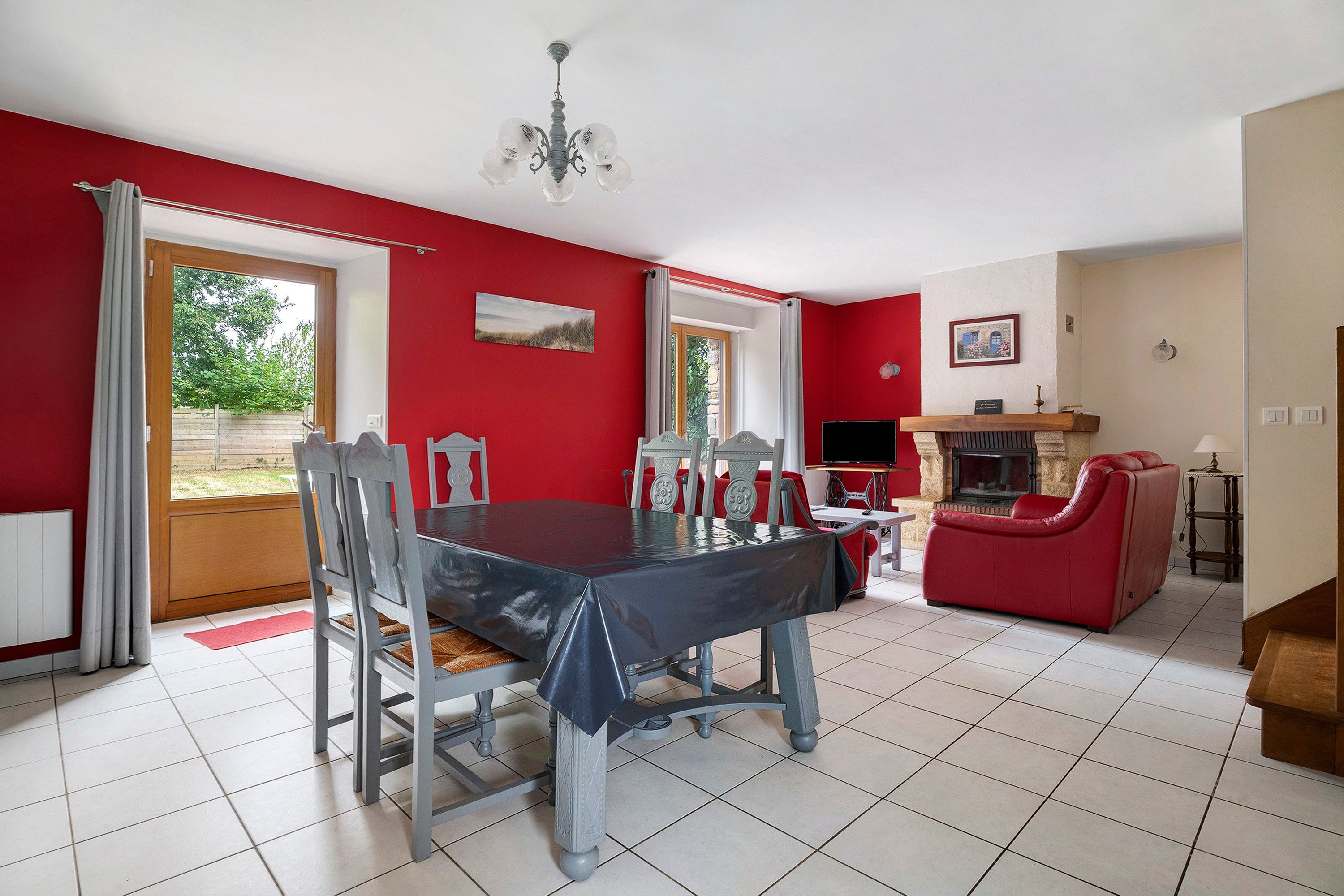 A dining area with a table and chairs, a red sofa, a fireplace, and a television.
