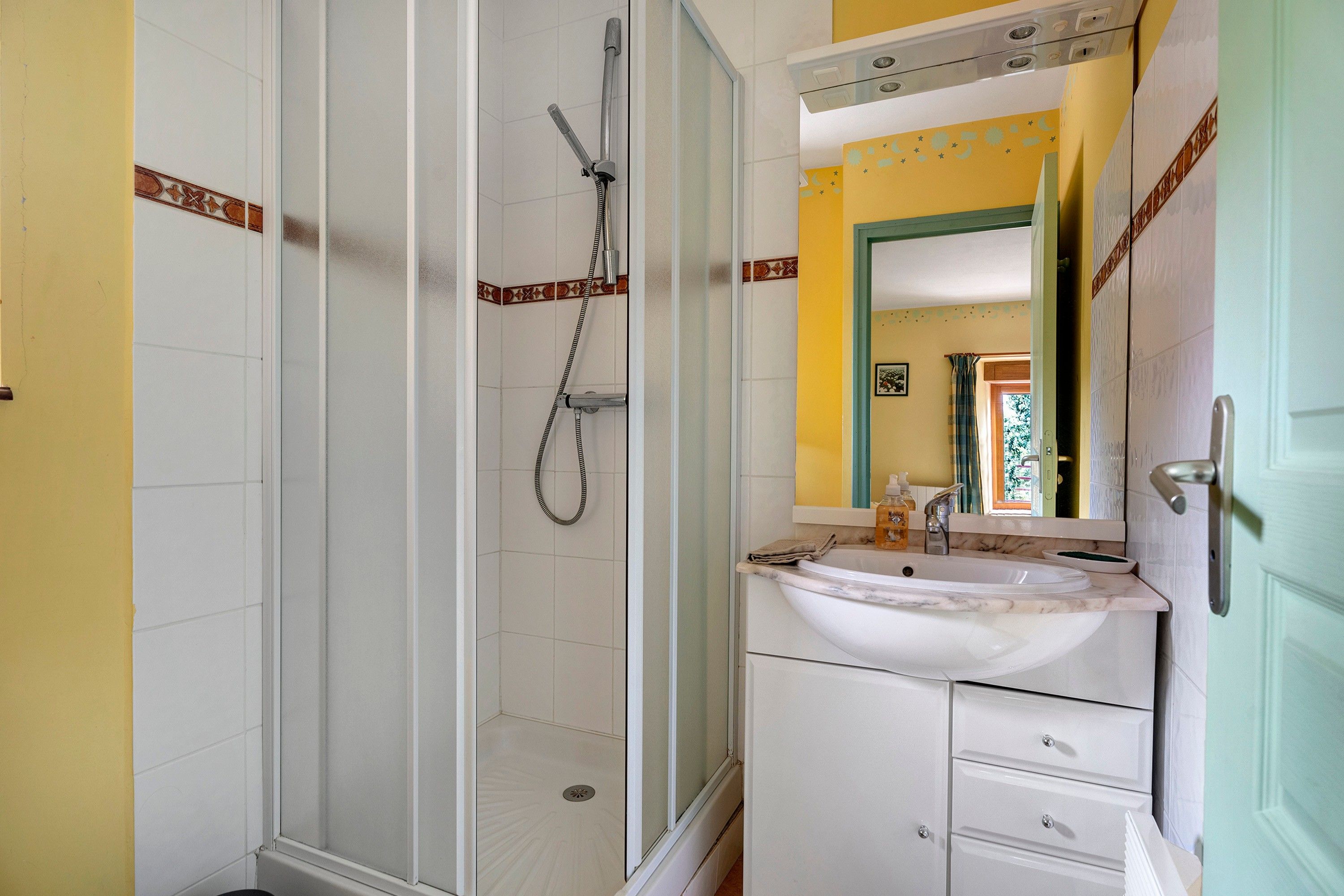 A bathroom with a shower, a sink, and a mirror.