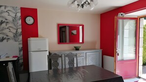 A kitchen with a refrigerator, a dining table, and a red-framed mirror.