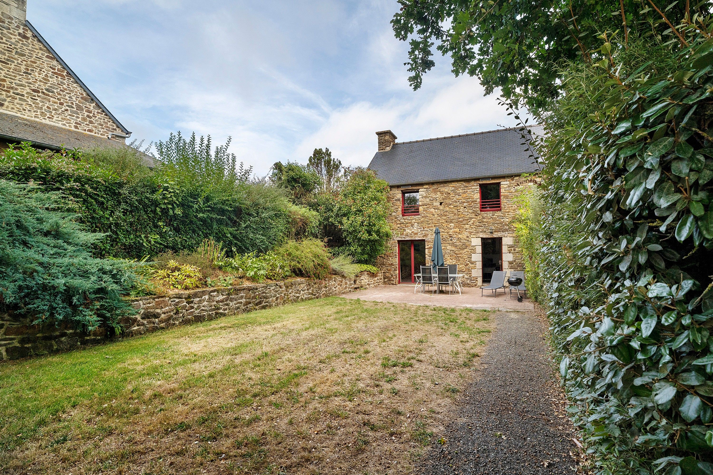 A stone house with a gravel yard and a patio with outdoor furniture.