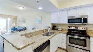 A modern kitchen with granite countertops, stainless steel appliances, and white cabinetry. - Carolinian Beach Resort 1830 (Myrtle Beach)