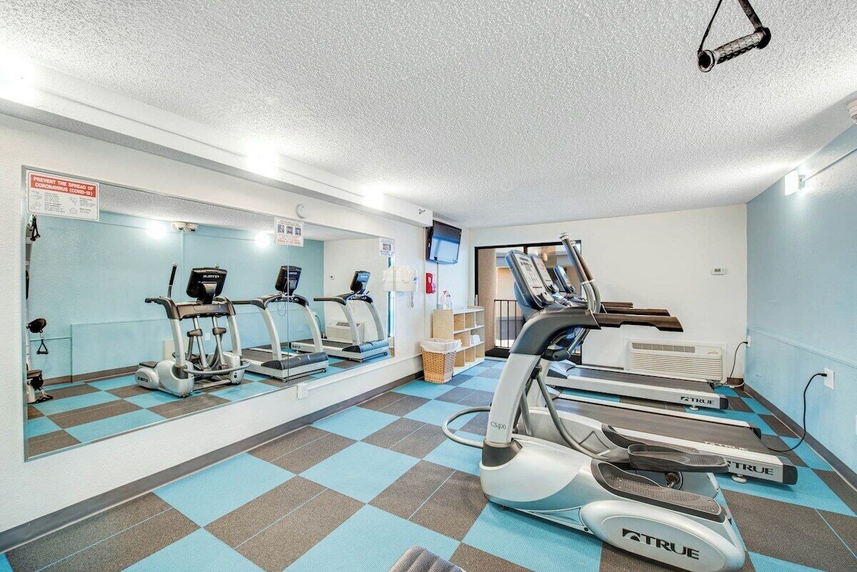 Ein Fitnessraum mit Laufbändern, Ergometer und einer Spiegelwand.