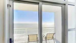 A balcony with two chairs, a view of the ocean, and a clear sky. - Carolinian Beach Resort 1830 (Myrtle Beach)