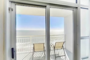 A balcony with two chairs, a view of the ocean, and a clear sky. - Carolinian Beach Resort 1830 (Myrtle Beach)