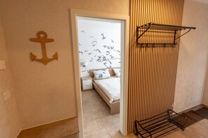 Una camera da letto con un letto, un comodino, una parete in legno con listelli verticali e un'asta per stendere i panni.