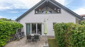 A two-story house with a patio area, a sliding glass door, and a green umbrella.