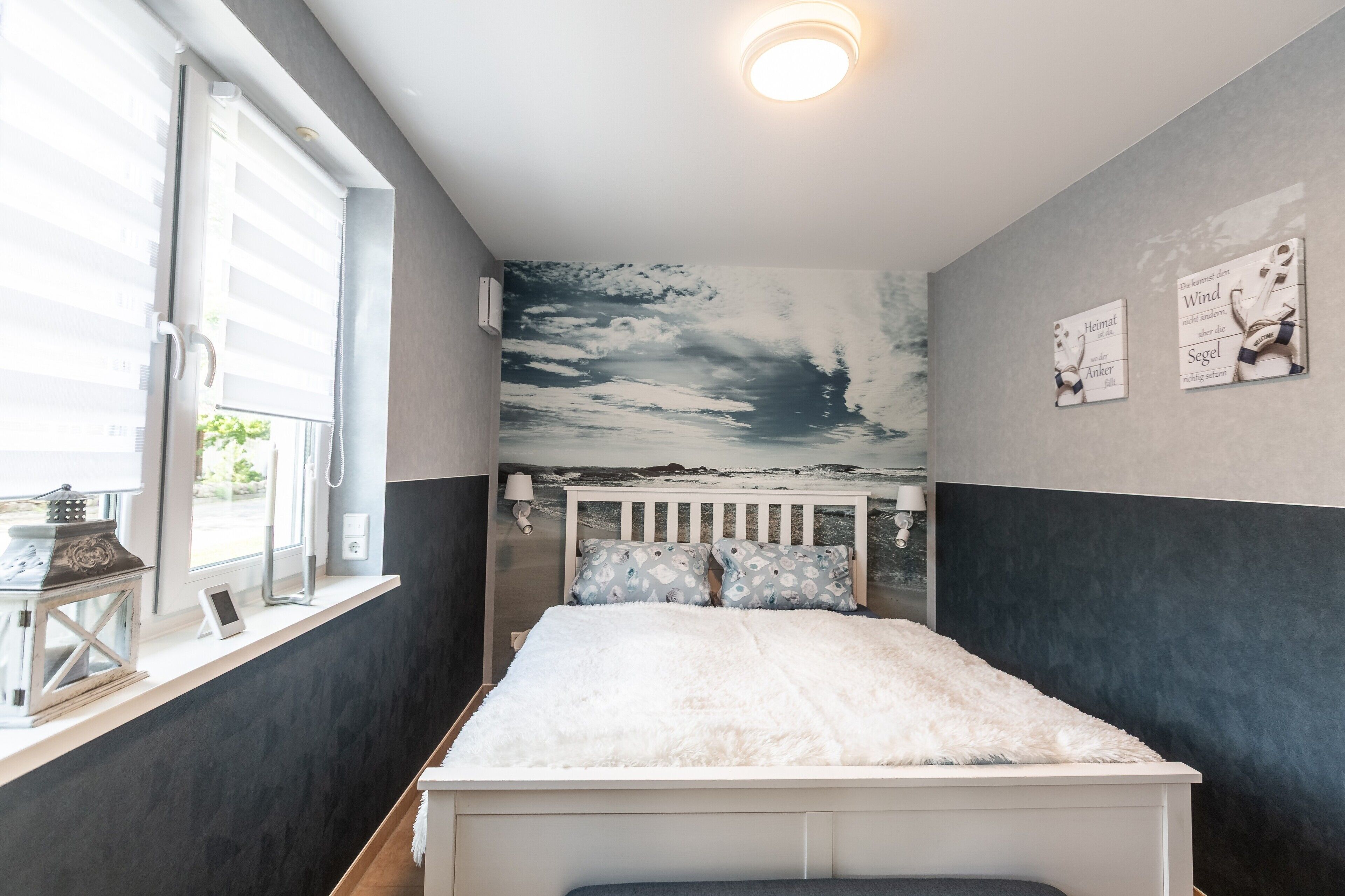 Une chambre à coucher avec un lit, une fenêtre, un climatiseur fixé au mur et un luminaire au plafond.