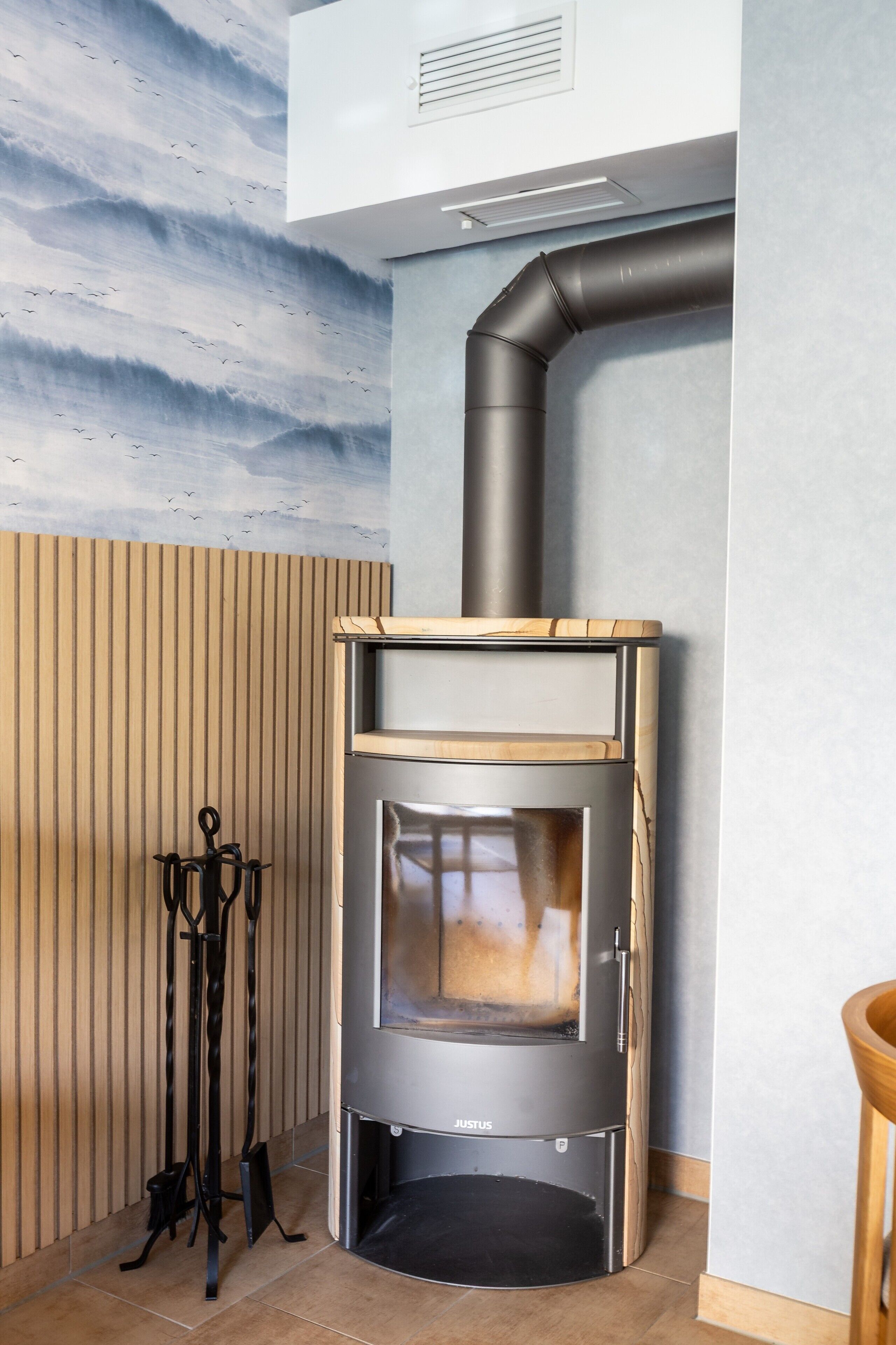 Une cuisine moderne dotée d’un poêle à bois encastré, d’un système de ventilation et d’un mur à lattes de bois.
