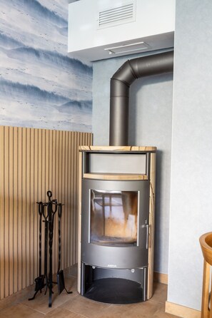 A modern kitchen with a built-in wood-burning stove, a ventilation system, and a wooden slatted wall. - Holiday Apartment Stralsund with Private Terrace, Garden & Wi-Fi (Stralsund)