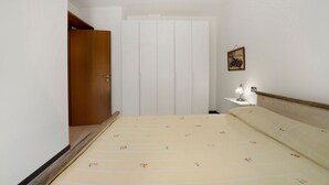 A bedroom with a bed, a nightstand, a wall-mounted lamp, and a door. - Azalea City Center Apartment with Shared Pool, Wi-Fi, and Air Conditioning (Induno Olona)