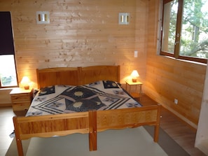 Ein Zimmer mit Holzwänden, einem Bett, zwei Nachttischlampen und einem Fenster.