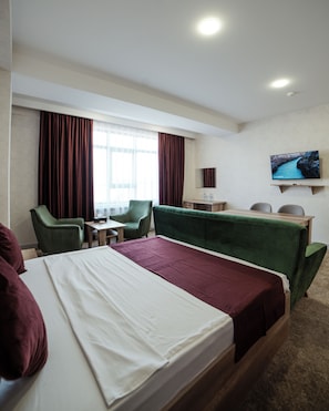 A hotel room with a bed, two chairs, a desk, a television, and a window with curtains. - Grand Kristal Baku (Baku)