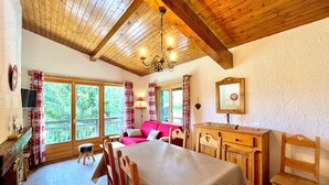 A cozy room with a wooden ceiling, a dining table with chairs, a sofa, and a window with curtains. - Ski-in/ski-out apartment with balcony in Combloux (Combloux)