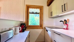 A compact kitchen with a toaster, coffee maker, and a window with a view of greenery. - Ski-in/ski-out apartment with balcony in Combloux (Combloux)