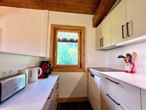 Eine kompakte Küche mit Toaster, Kaffeemaschine und einem Fenster mit Blick auf Grünflächen.