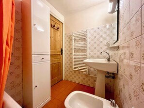 A bathroom with a white sink, a wooden door, and patterned tiles.