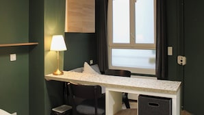 A compact room with a desk, chair, and a window with curtains. - Cozy Studio in Central Paris (16m²) (Paris)
