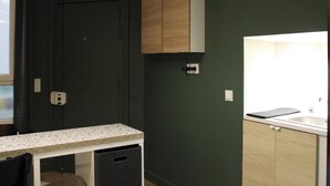A kitchen with dark green walls, wooden cabinets, a granite countertop, and a window. - Cozy Studio in Central Paris (16m²) (Paris)