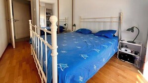 A bedroom with a bed, a wardrobe, a bedside table, and a lamp. - Apart with loggia overlooking the canal, parking (La Rochelle)