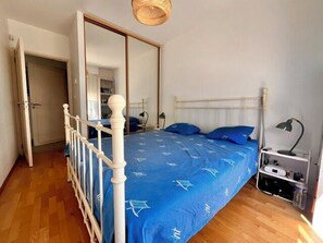 Ein Schlafzimmer mit einem Bett, einem Kleiderschrank, einem Nachttisch und einer Lampe.