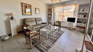 A living room with a sofa, coffee table, and bookshelves. - Apart with loggia overlooking the canal, parking (La Rochelle)