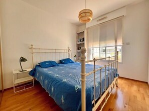 A bedroom with a bed, bedside table, lamp, and a window. - Apart with loggia overlooking the canal, parking (La Rochelle)