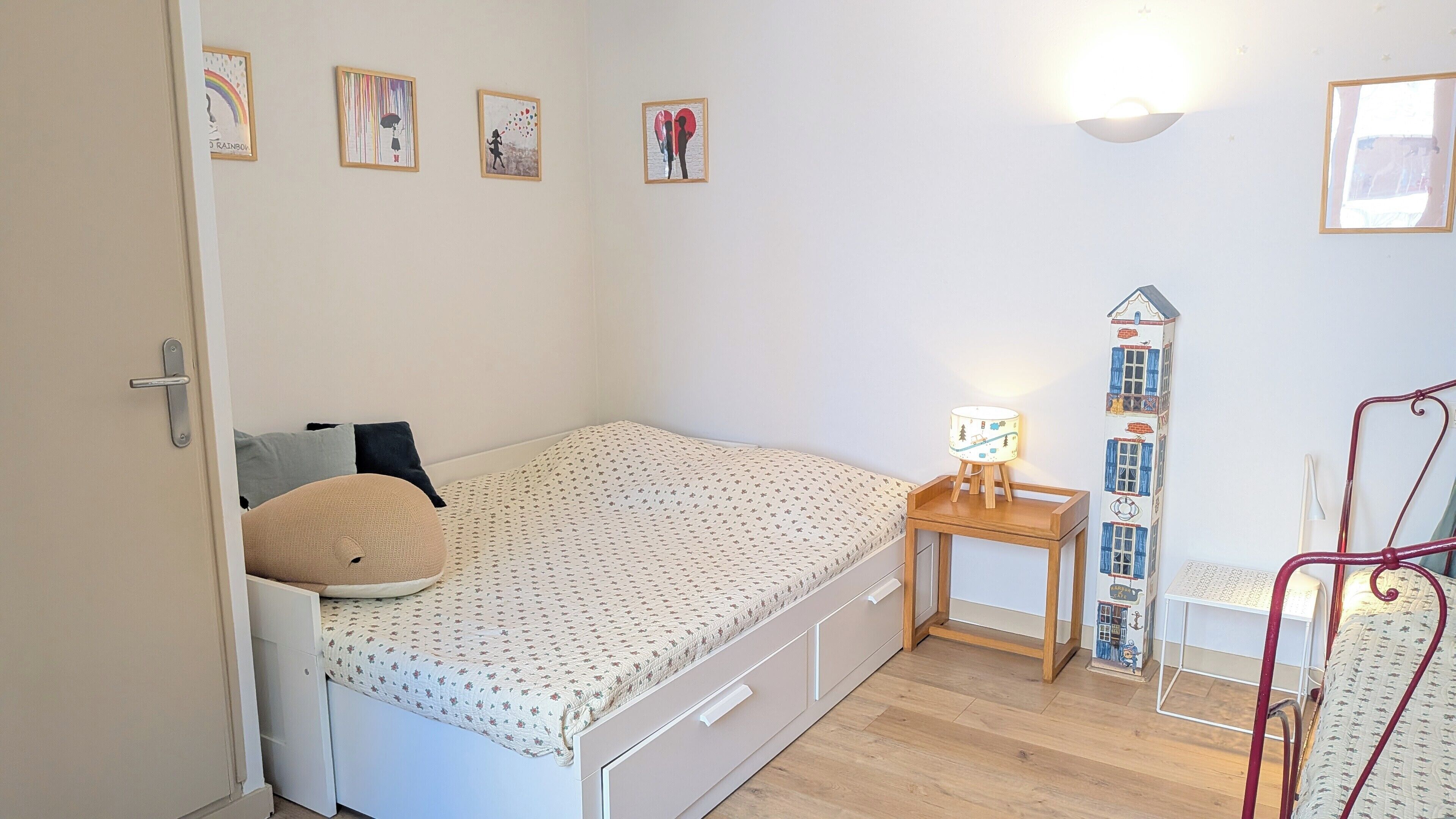 Une chambre à coucher avec un lit, une table de chevet, une lampe et des œuvres d’art murales.