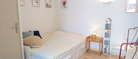 Une chambre à coucher avec un lit, une table de chevet, une lampe et des œuvres d’art murales.