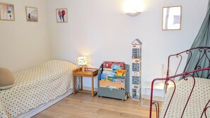 A room with two beds, a nightstand with a lamp, a bookshelf, and a window with curtains. - Charming large house in Velleron near Luberon. (Velleron)