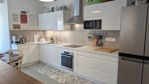A modern kitchen with white cabinetry, a stainless steel refrigerator, a built-in microwave, and a dishwasher. - Charming large house in Velleron near Luberon. (Velleron)
