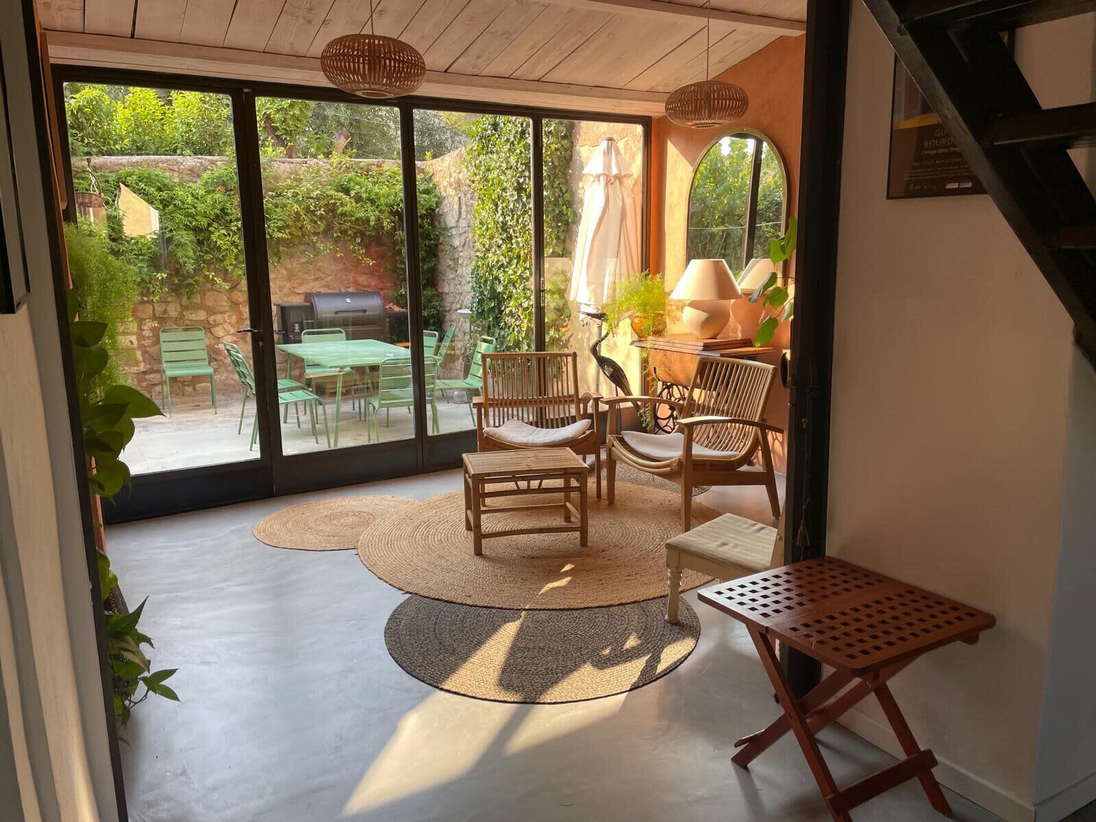 A room with a sliding glass door leading to an outdoor patio with green chairs and a table.