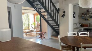 A modern interior with a staircase, dining area, and a living room with a sofa and coffee table. - Charming large house in Velleron near Luberon. (Velleron)
