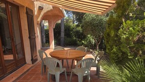 Eine Terrasse im Freien mit einem runden Holztisch und sechs Stühlen.