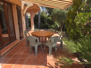 Eine Terrasse im Freien mit einem runden Holztisch und sechs Stühlen.