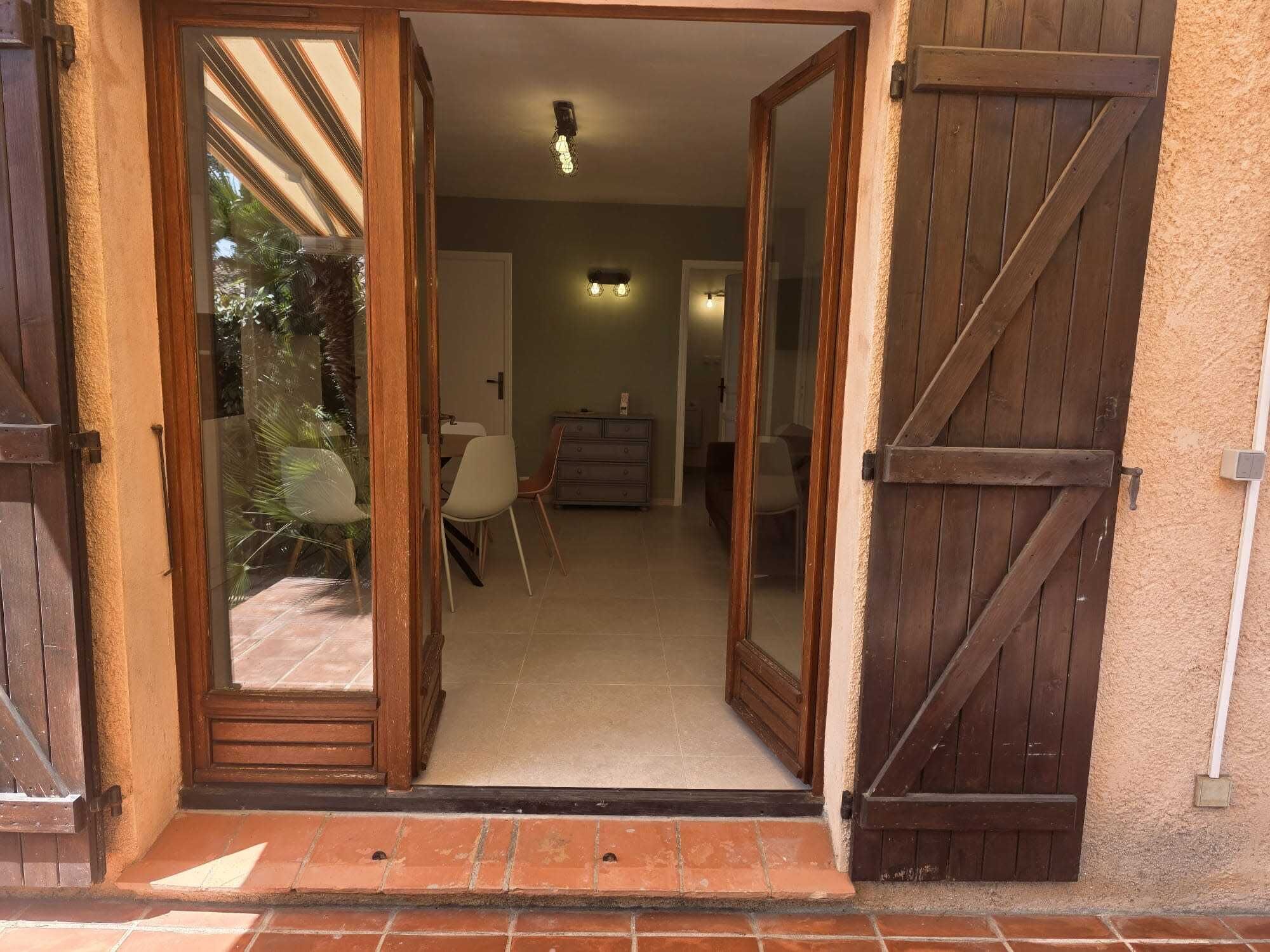 A doorway leading into a room with a dining area, a dresser, and a ceiling light fixture.