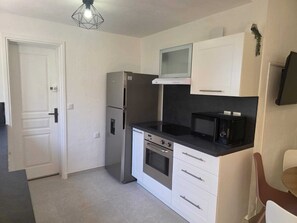 Eine kleine Küche mit Kühlschrank, Backofen, Mikrowelle und einer kompakten Arbeitsfläche.