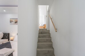 Eine Treppe führt zu einem Schlafzimmer mit einem Bett, einem Nachttisch und einer Lampe.