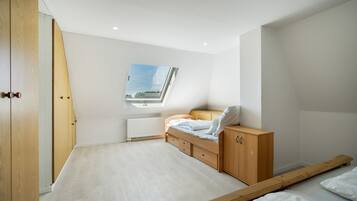 Ein Schlafzimmer mit Dachfenster, einem Bett, einem Holzschrank und einer Heizung.
