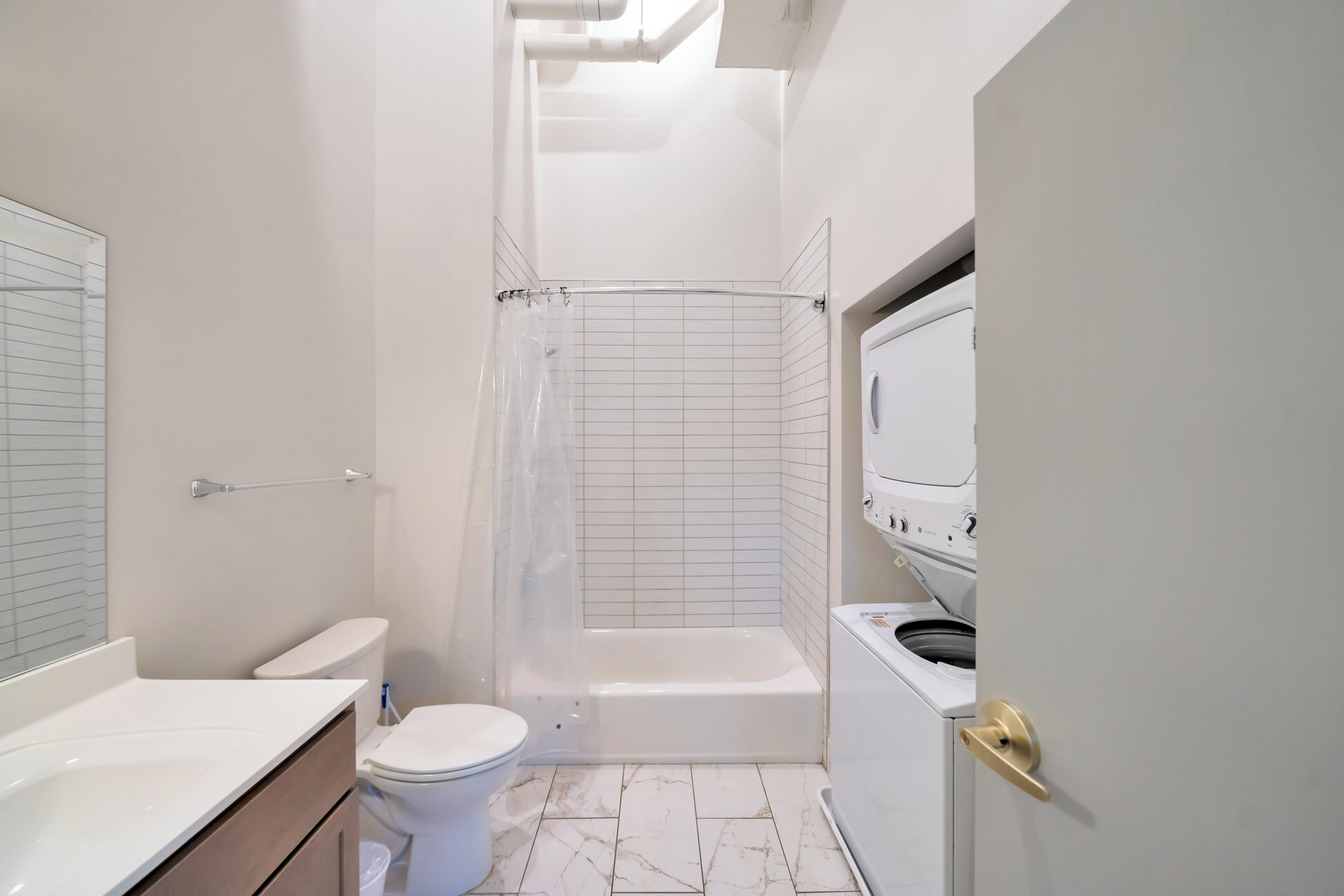 Een badkamer met toilet, douche en wasmachine.