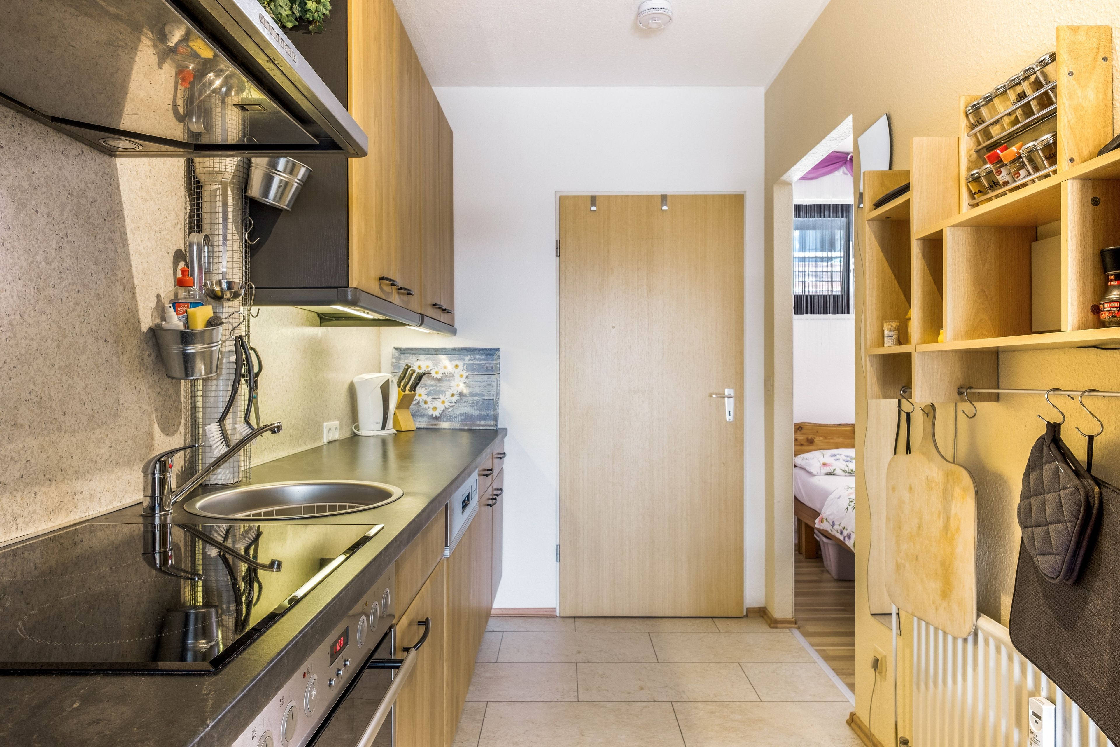 A compact kitchen with a stainless steel sink, a stove, and wooden cabinets.