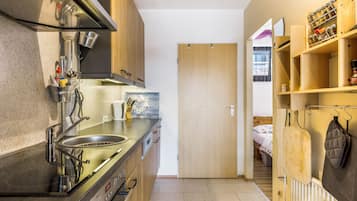A compact kitchen with a stainless steel sink, a stove, and wooden cabinets.