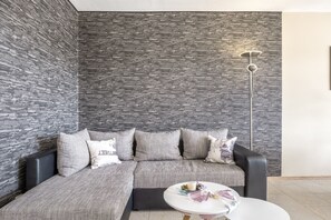 A modern living room with a sectional sofa, a round coffee table, and a floor lamp. - Apartment 'Beautiful View with Pool', Balcony & Wi-Fi (Schonach im Schwarzwald)