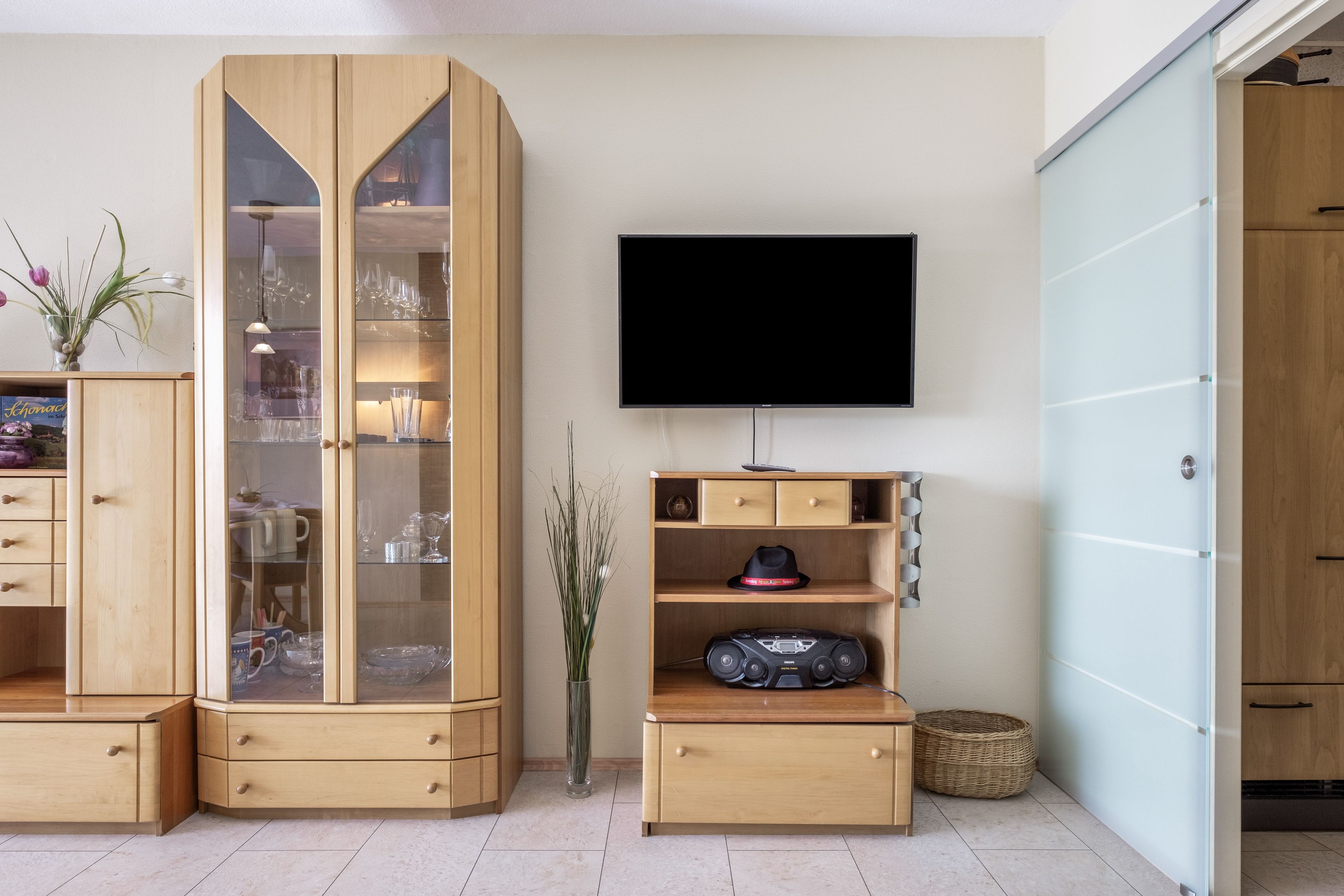 Un salon moderne avec un meuble en bois, un téléviseur à écran plat et une petite table sur laquelle se trouve une radio.