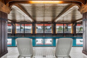 A pool area with wooden beams, a tiled floor, and two white chairs. - Apartment 'Beautiful View with Pool', Balcony & Wi-Fi (Schonach im Schwarzwald)