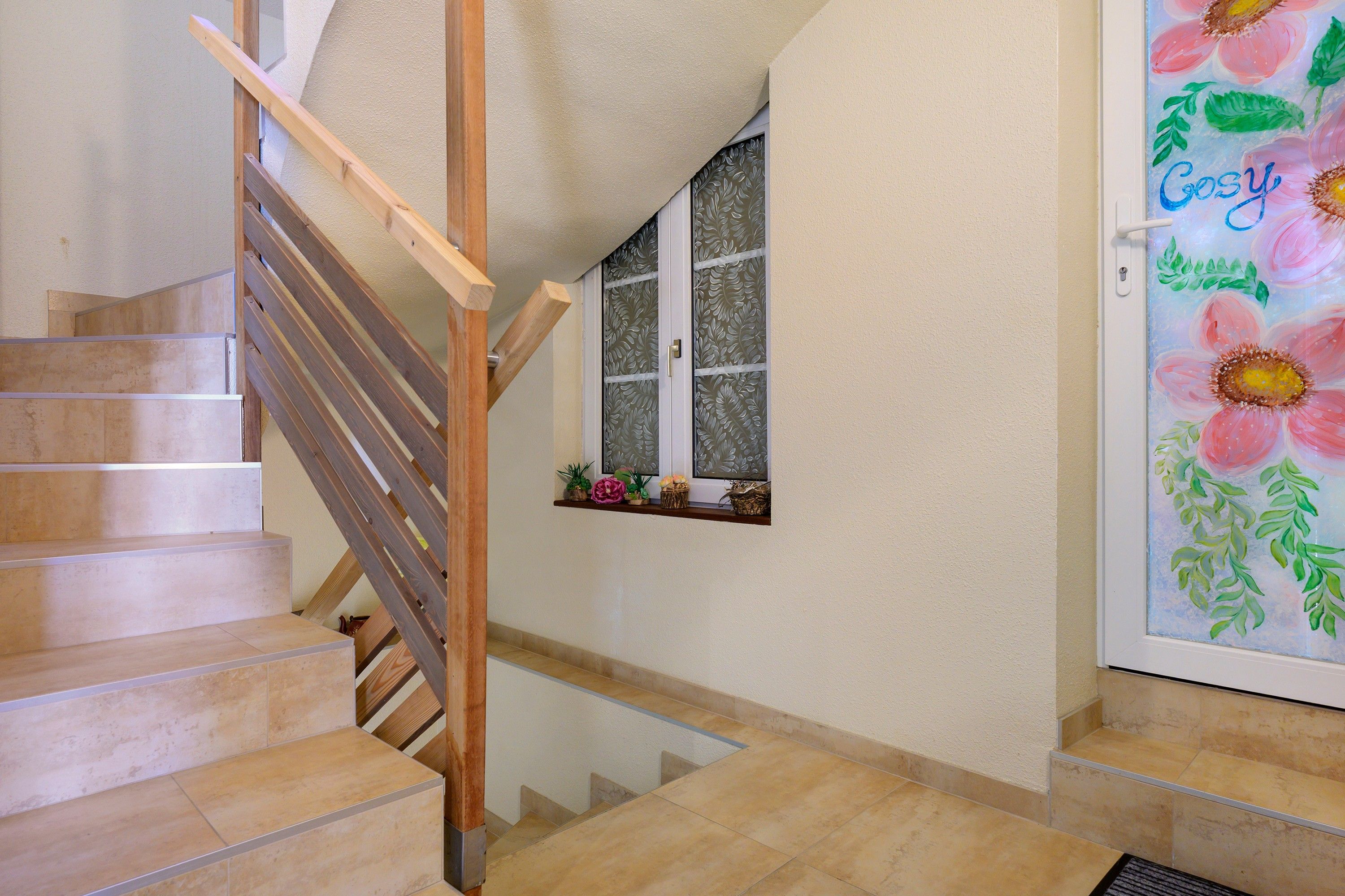 Una escalera con barandillas de madera y baldosas color beige.