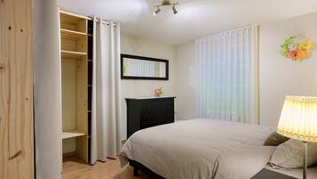 Une chambre à coucher avec un lit, une commode, un miroir et une fenêtre avec des rideaux.