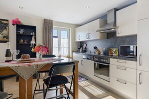 A modern kitchen with white cabinets, a stainless steel stove, and a microwave.
